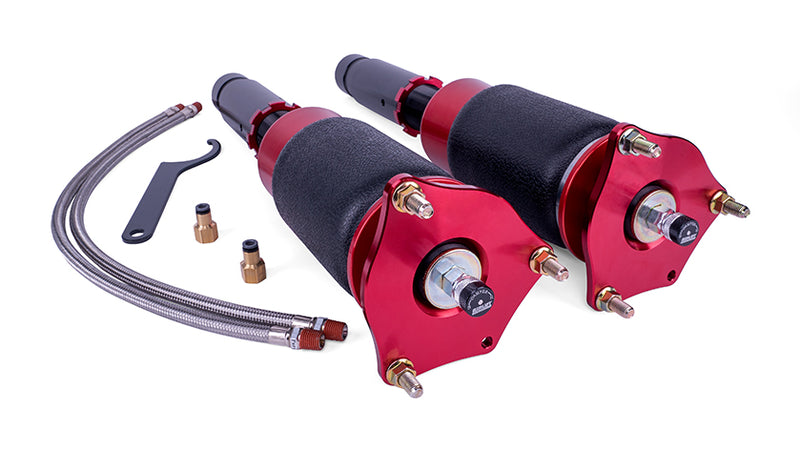 A pair of black and red sleeve style automotive air springs with monotube struts, 2 braided leader air lines with installation fittings and tool.
