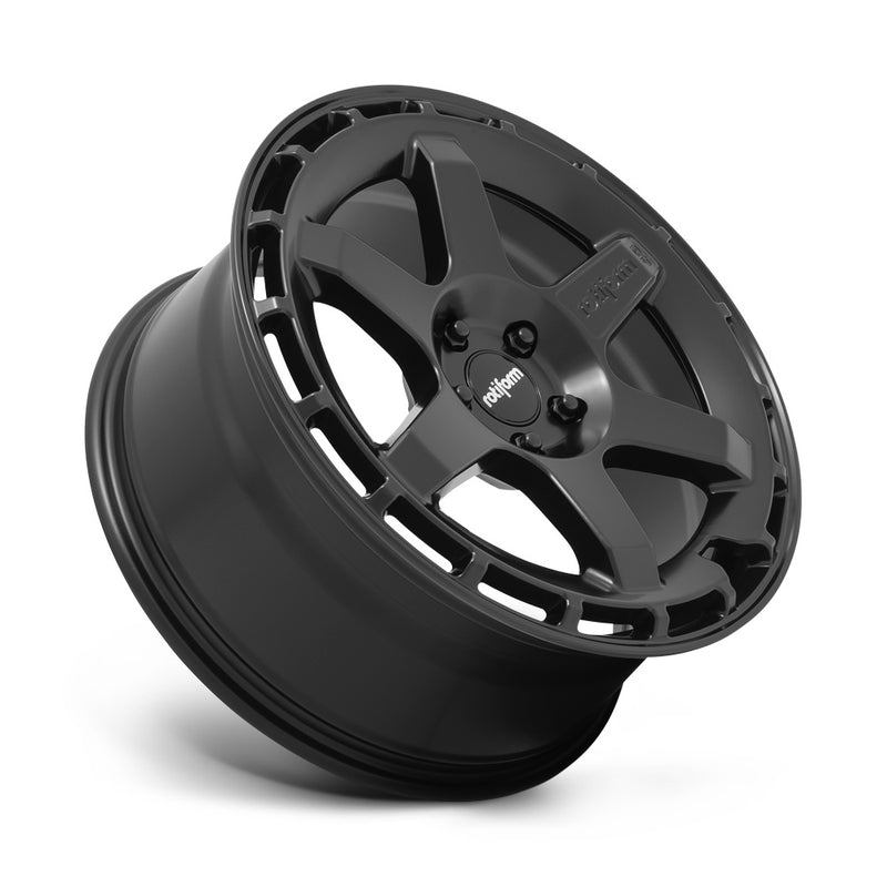 Tilted side view of a Rotiform Ken Block Signature Wheel KB1 is a cast aluminum 6 Spoke automotive wheel in a matte black finish with a Rotiform and Ken Block Logo embossed in one spoke along with a Rotiform silver logo center cap.