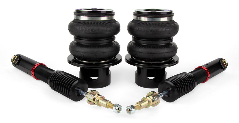 A pair of black double bellows air bags and a pair of black monotube automotive shocks.