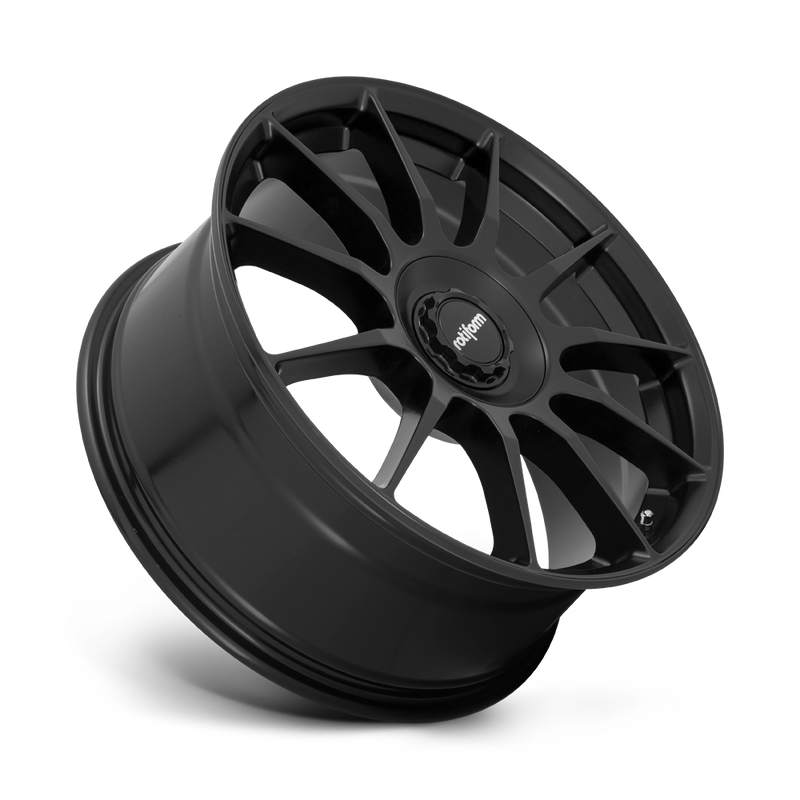 Tilted side view of a Rotiform DTM monoblock cast aluminum 11 spoke automotive wheel in a satin black finish with a Rotiform black center cap having a silver Rotiform logo.