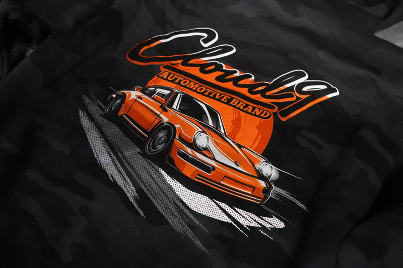 Close up of the rear of a gray camo hoodie showing the orange Porsche graphic along with the Cloud 9 Automotive Brand logo.