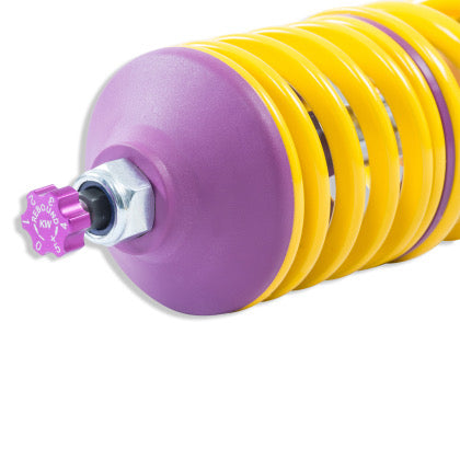 Close up of the end of a coilover yellow spring showing a purple rebound adjustment knob.