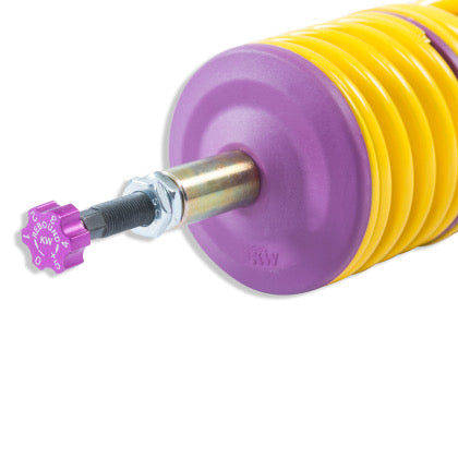 Close up of the end of a coilover yellow spring showing a purple rebound adjustment knob.