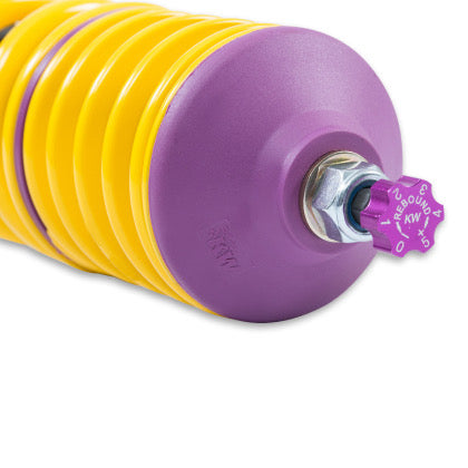 Close up of purple rebound adjustment knob at end of coilover strut with fitted yellow spring and purple accented end fitment.