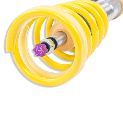Close up of the end of ayellow spring mounted on a coilvoer showing the purple rebound adjustment knob.