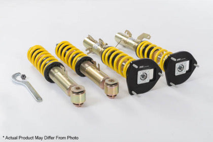 Four assembled vehicle coilover struts with yellow springs