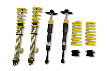 Two assembled vehicle suspension coilovers and two unassembled coilovers with unsleeved black struts and springs shown separately