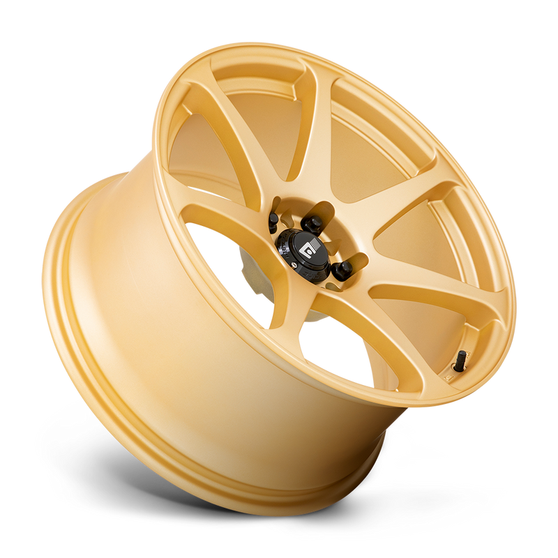 Tilted side view of a Motegi Racing Battle cast aluminum 7 spoke automotive wheel in a gold finish with a black center cap displaying a silver Motegi logo.
