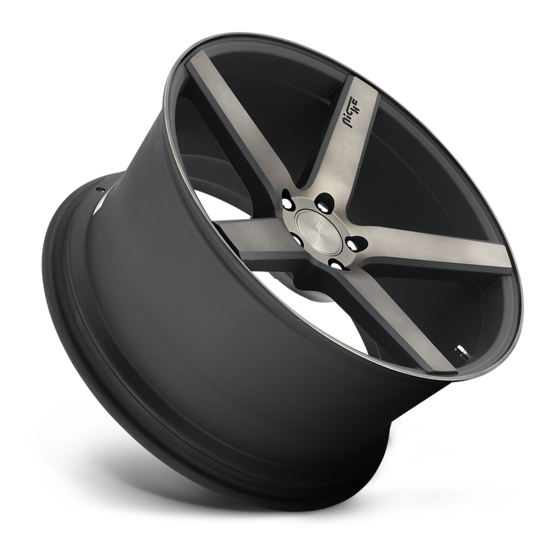 Tilted side view of a Niche Milan monoblock cast aluminum 5 spoke automotive wheel in a matte black machined double dark tint finish with an embossed Niche logo in one spoke and a Niche silver logo center cap.