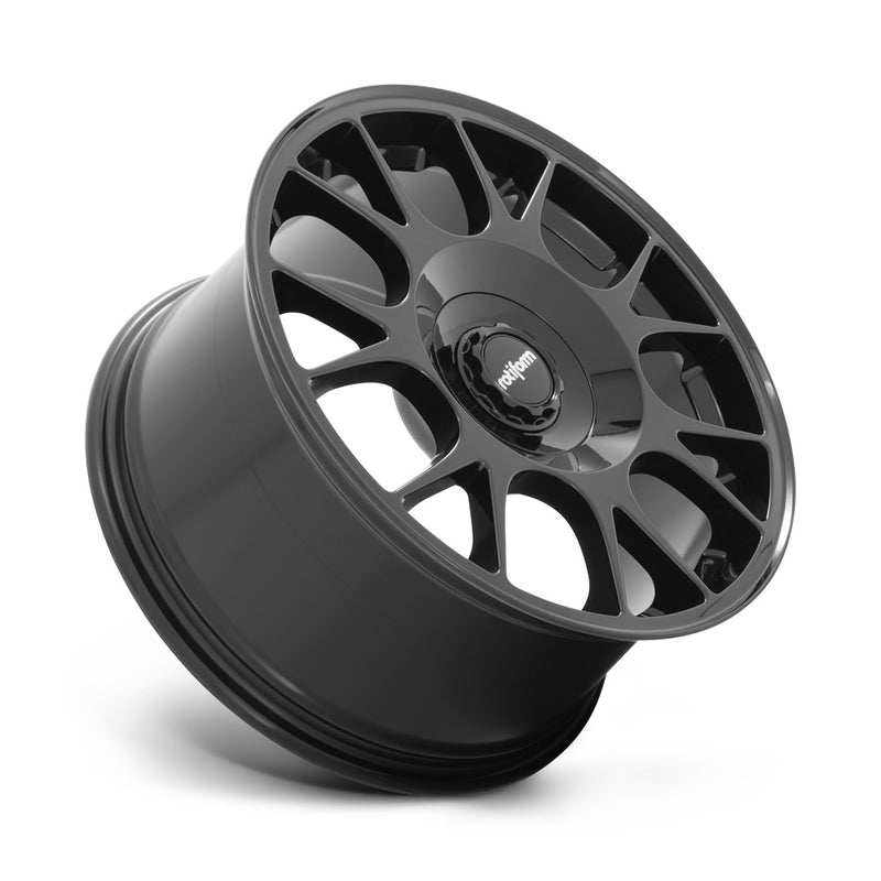 Tilted side view of a Rotiform TUF-R monoblock cast aluminum 7 spoke design automotive wheel in gloss black finish with a black center cap with a silver Rotiform logo.
