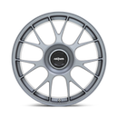 Front face view of a Rotiform TUF a monoblock forged aluminum 7 Y shape spoke automotive wheel in a satin titanium finish with the word Forged embossed in the bead ring and a black center cap with a silver Rotiform logo.