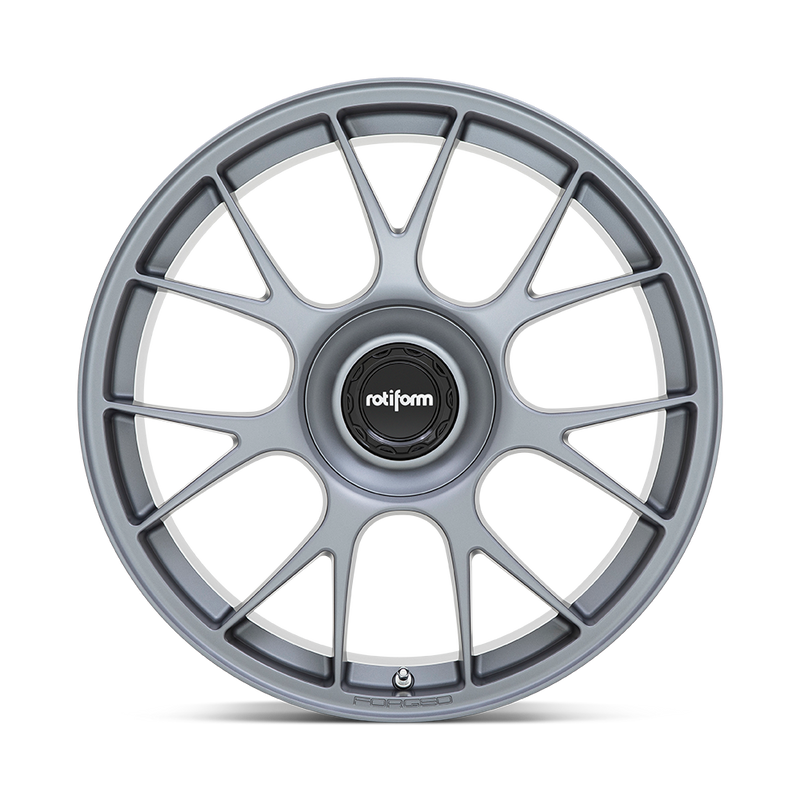 Front face view of a Rotiform TUF a monoblock forged aluminum 7 Y shape spoke automotive wheel in a satin titanium finish with the word Forged embossed in the bead ring and a black center cap with a silver Rotiform logo.